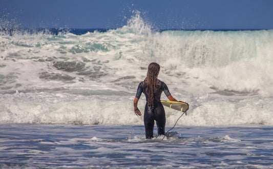 Chica entrando a surfear en el mar